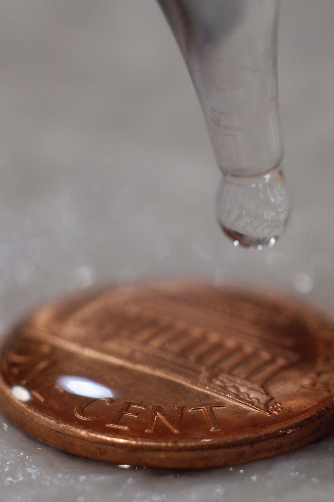 Macro photograph of water beading on a penny due to high surface tension